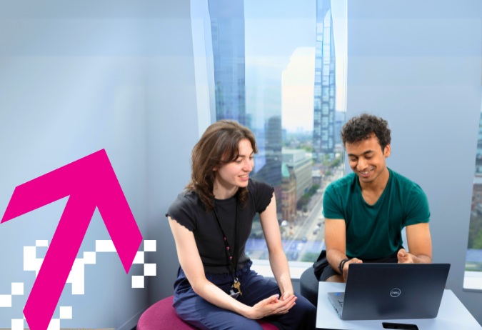 Two people are sitting down looking at a laptop