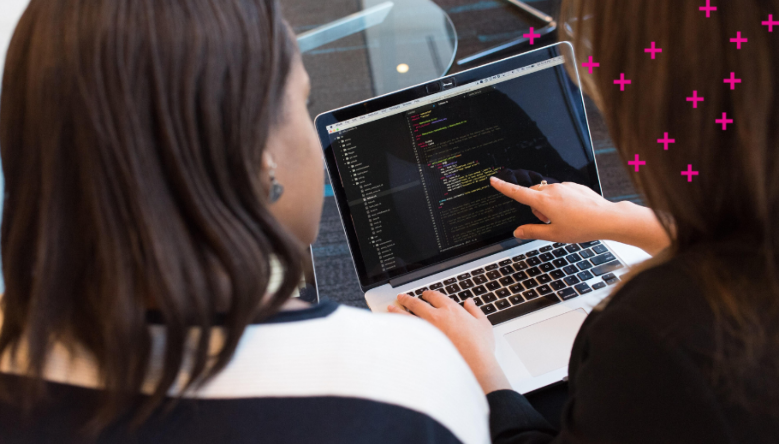 Two women typing code onto a computer