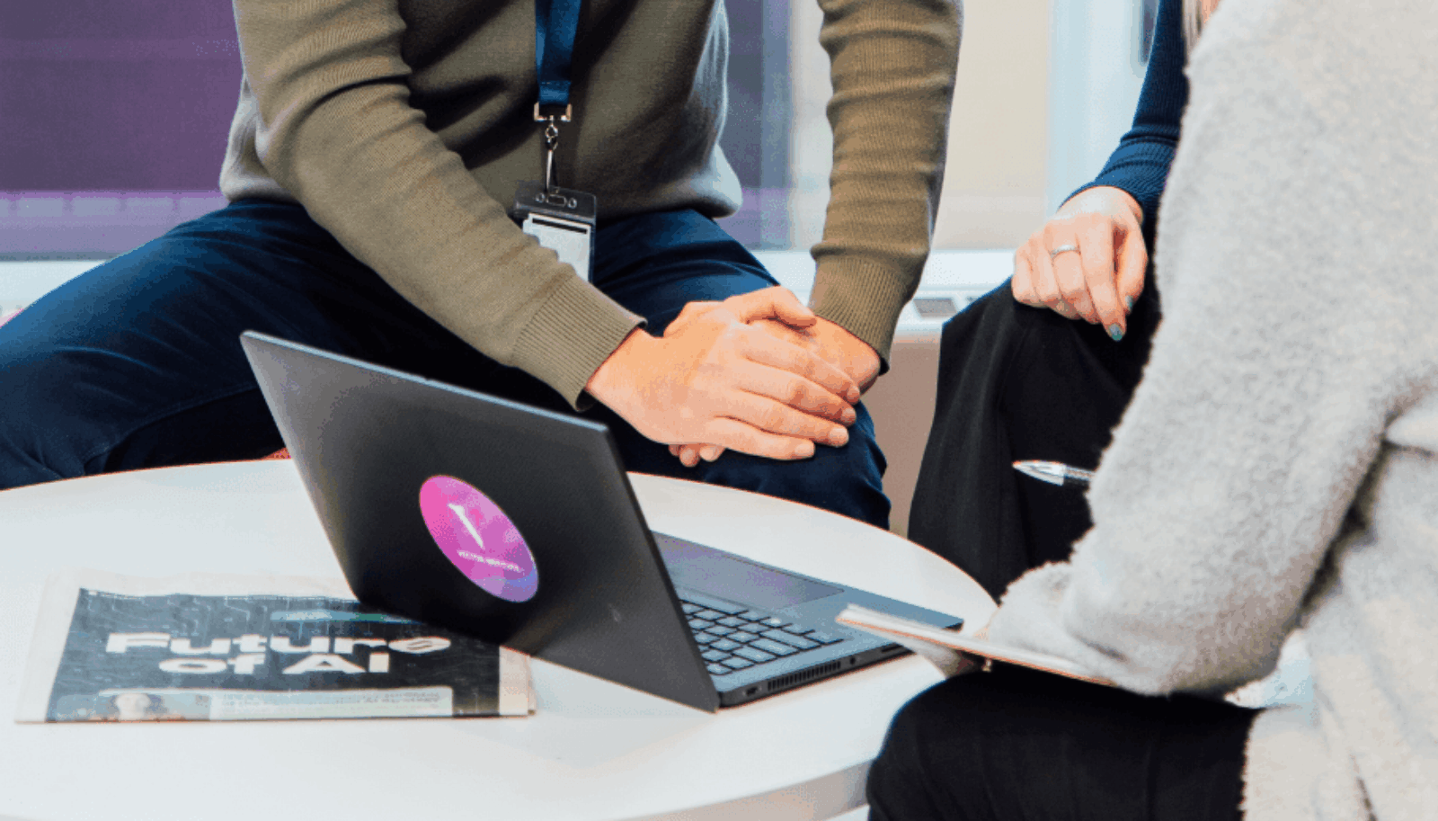 Three people looking at a laptop with a Vector logo sticker