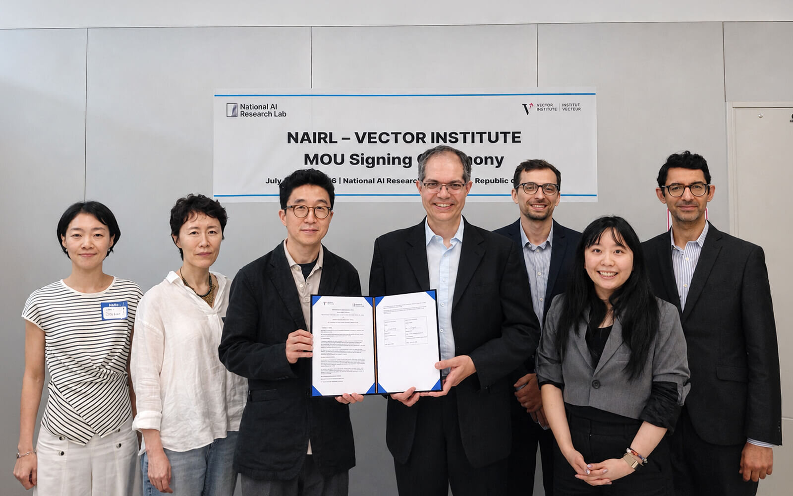 Vector Institute and National AI Research Lab representatives presenting a signed document.